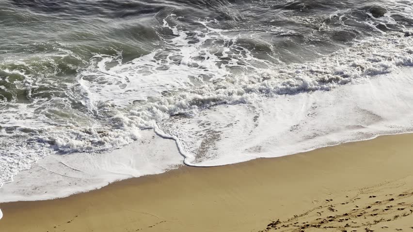 Beach sand sea water summer background. Sand beach desert texture. White foam wave sandy seashore top view.
