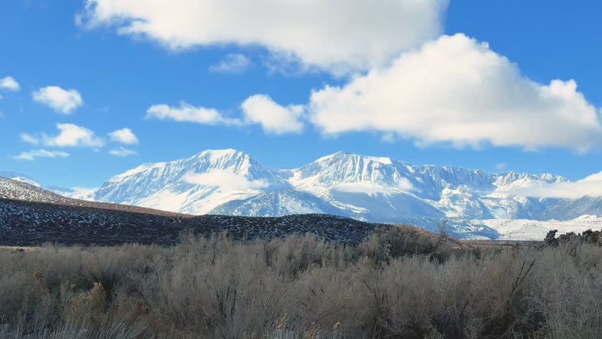 Panning shot of Jagged Lithoid Tufa towers at the South Tufa Grove, Mono Lake State Natural Reserve, Mono County, CA, USA, set against the snow-capped Sierra Nevada peaks along Highway 395