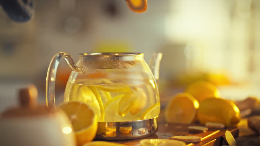 In the warm morning sunlight, a man's hands carefully prepare a revitalizing tea by adding slices of pungent ginger rhizome, rich in vitamins and minerals, to a teapot