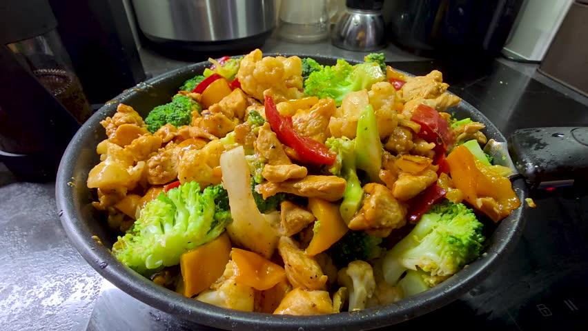 Chicken, broccoli, pepper and cauliflower stir-fry, fresh roasted vegetables and tender pieces of chicken mixed together in a hot pan on the hob