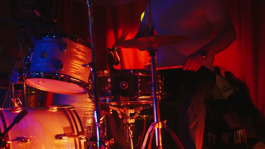 Handheld cinematic shot. A drummer in a jazz nightclub