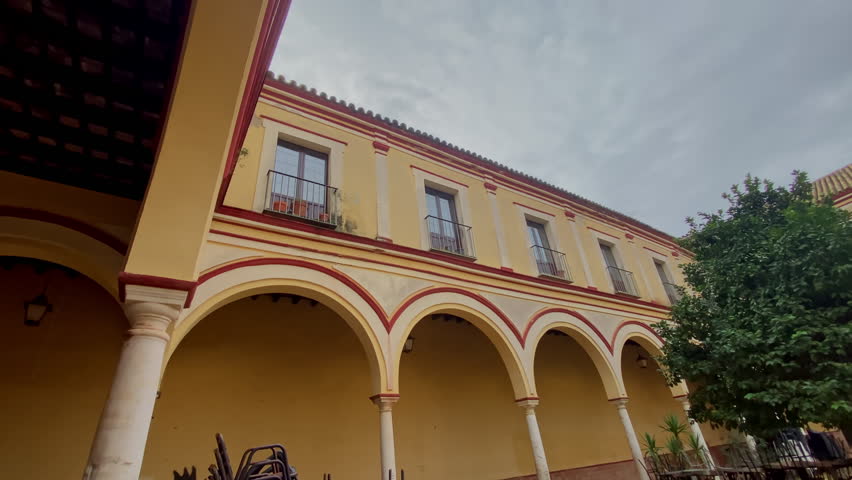 the Quiet cloistered courtyard with arches, orange trees and empty chairs, soft light after the storm in an old Andalusian building