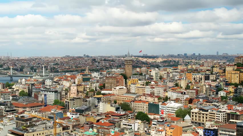 Aerial drone view of Istanbul, Turkey, showing residential buildings surrounding Galata Tower with the Golden Horn waterway in the background.