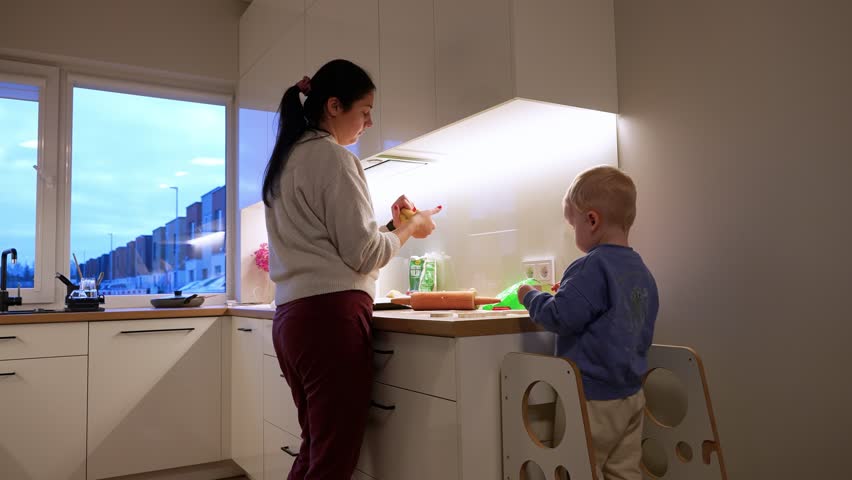 In a cozy, well-lit kitchen, a mother and her young child engage in a bonding cooking session. The serene evening light adds a warm ambience to this intimate family moment.