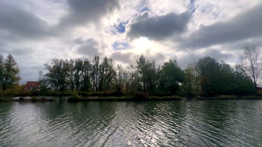 Rijkevorsel, Antwerpse Kempen, Belgium, Rough waters beneath overcast skies in nature scene, Cresting waves under stormy clouds with silhouette trees backdrop