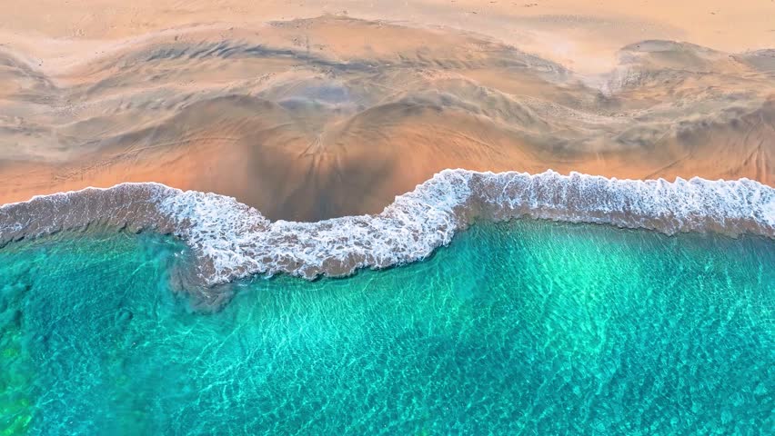 A tropical sea beach in the summer outdoors. Aerial view of a wave on the beach sand. Summer seascape. Ocean wave background texture. Drone view of the sea. Aerial view. Blue ocean wave.