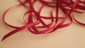 Thin red satin ribbon for wrapping presents. Unfolding a pack or ribbon. Christmas preparation. Valentines day gifts wrapping. - Powered by Shutterstock - Get 15% off with code: PIKWIZARD15