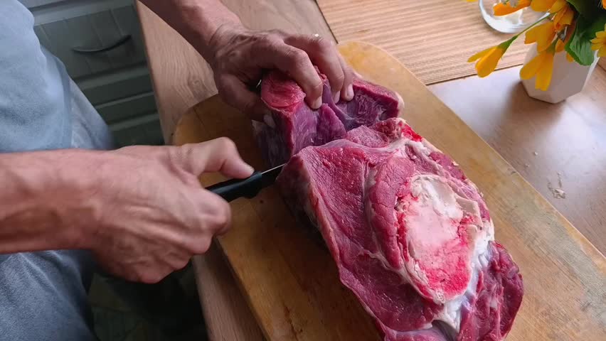 Slicing beef. The coo
k carefully slices a fresh piece of beef tenderloin on a cutting board.