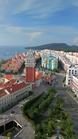 Aerial view of coastal town with iconic clock tower overlooking the sea and Kiss Bridge on Phu Quoc Island, Vietnam. Mediterranean style architecture, seaside promenade and tropical travel destination