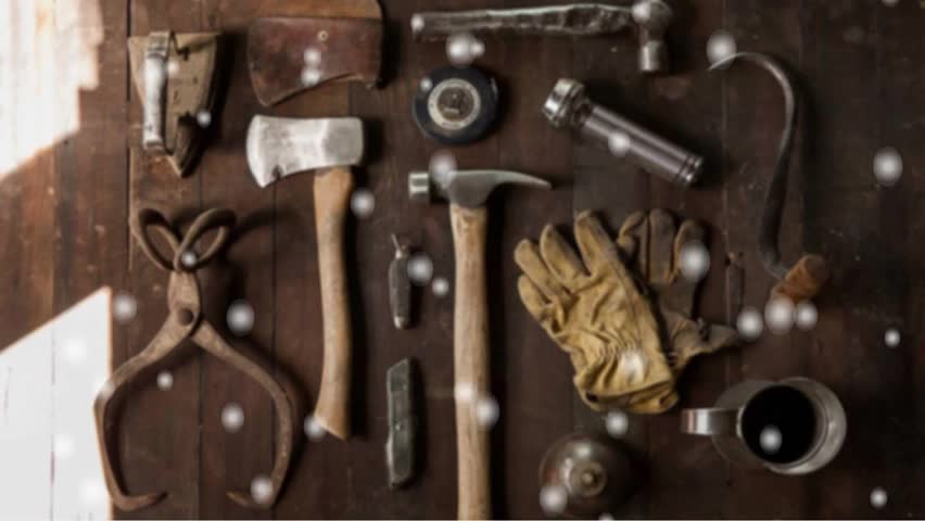 "A top-down collection of vintage hand tools, including axes, hammers, and leather gloves, neatly arranged on a rustic wooden surface with soft bokeh light overlays."