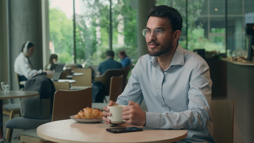 Indian business man Arabian guy male businessman in cafe paying with mobile phone service NFC pay order payment visitor in cafe client with smartphone cashless online bank waiter holding terminal