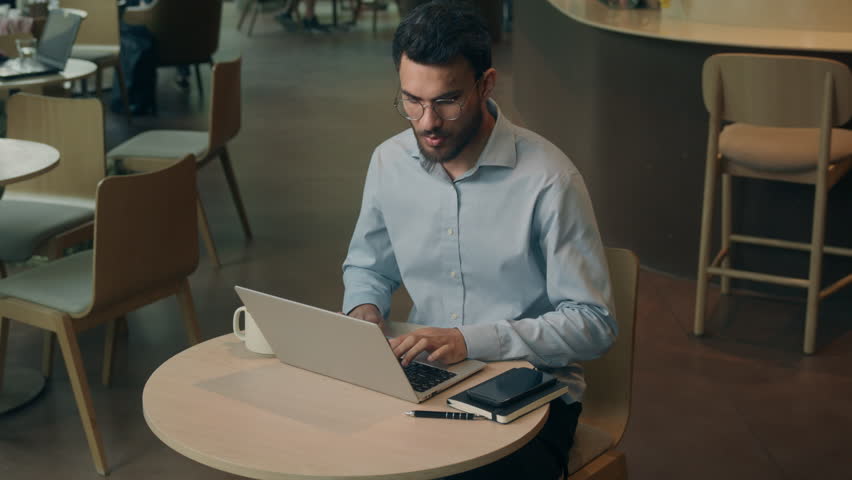 Indian business man Arabian businessman with laptop take wired headphones broken upset sad frustrated with crash earphones in cafe male guy executive specialist working computer trying answer call