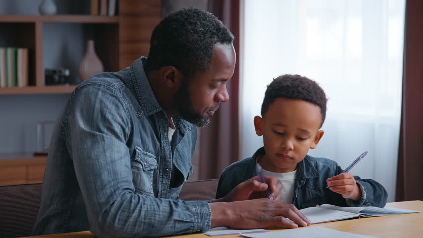 African American family clever father help son writing letters write homework man teacher tutor teaching little ethnic boy kid child pupil preparing to school dad distant busy elementary education