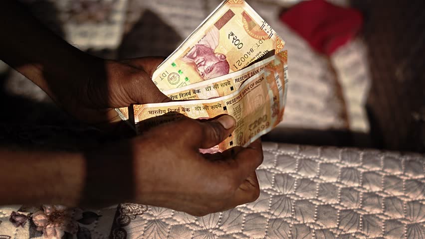 Close-up shot of hands counting Indian rupee notes, showing cash transaction and financial activity.