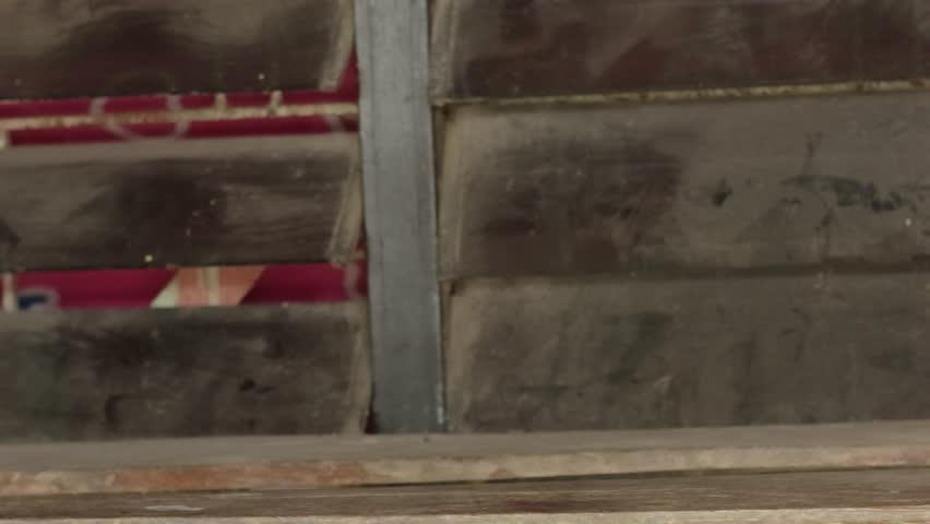 A hand placing a gold trophy with red and white ribbons on a wooden table against a background of old wooden windows