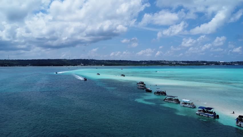 Aerial drone footage of turquoise shallow waters with small boats resting over sandbanks in a tropical paradise. Clear blue sea, calm ocean and summer travel concept.