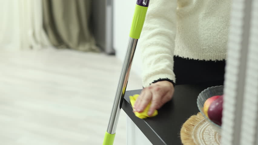 Woman cleans kitchen at home, wipes cabinets and shelves,places plates, rinses cloth, moves muffins into container.Pregnant female rests,drinks water,wipes kitchen counter and puts spoons into drawer.