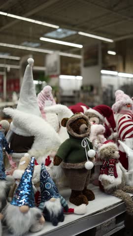 Vertical screen christmas plush toys and festive figurines fill store shelf with gnomes bears and winter characters creating cheerful holiday shopping scene