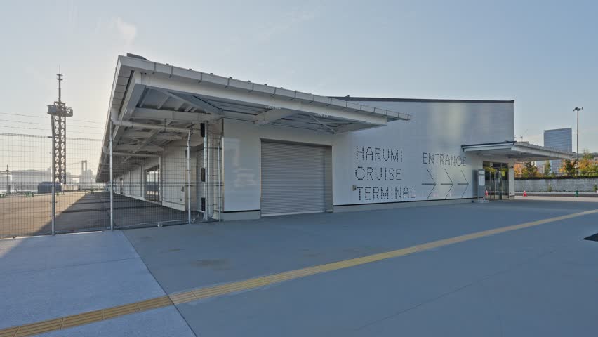 A wide, establishing shot capturing the clean, modern white exterior and explicit "HARUMI CRUISE TERMINAL" signage