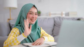 Asian Muslim woman student learning online class in living room at home. Beautiful girl wearing hijab sit on floor, using digital laptop computer study courses by virtual remote online in cozy house. - Powered by Shutterstock - Get 15% off with code: PIKWIZARD15