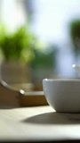 Low angle close up of white ceramic teacup on wooden table with steam rising in bright morning sunlight and shadows - Powered by Shutterstock - Get 15% off with code: PIKWIZARD15