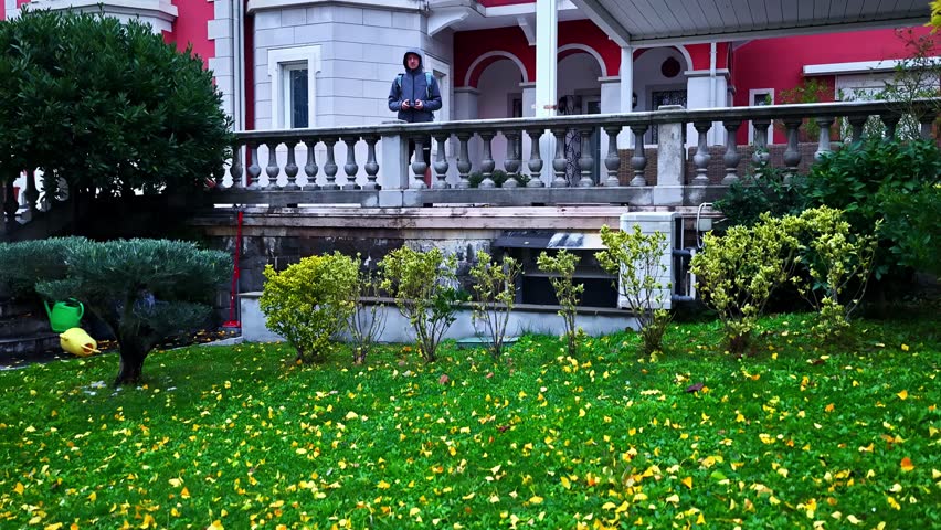 Person in hoodie stands outside colorful Italian villa in Trieste