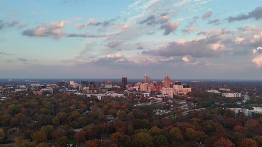 Aerial view of a mid-sized American city skyline rising above autumn forest.