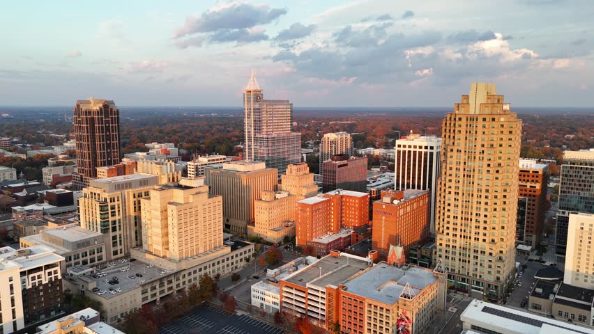 Drone footage of downtown Raleigh, North Carolina, USA during golden hour with warm sunlight and clear skyline