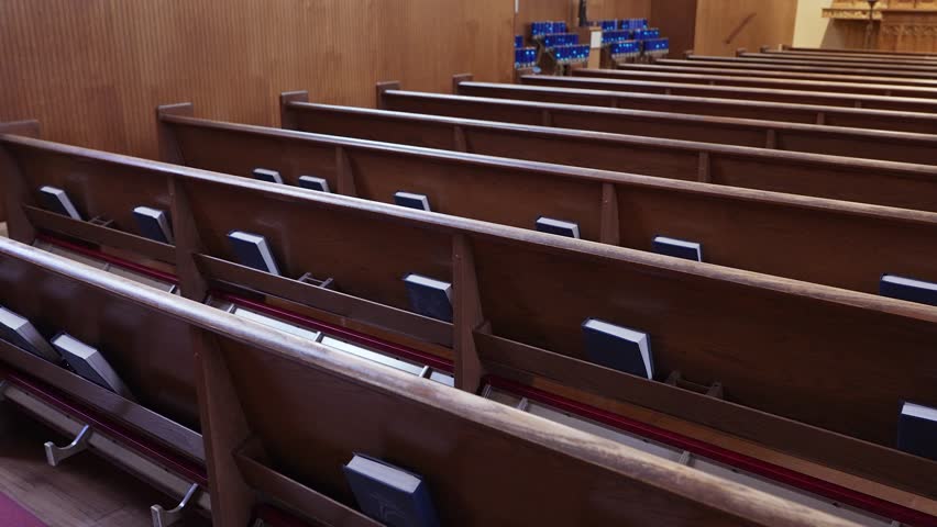 Walking down aisles of a church looking at Bibles, candles, and wooden church pews.