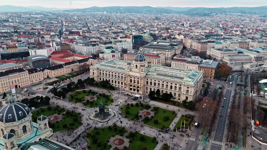 Aerial drone shot of the Austrian National History Museum in Vienna, showing the grand historic façade with surrounding city streets and rooftops, framed by the Vienna cityscape under clear winter