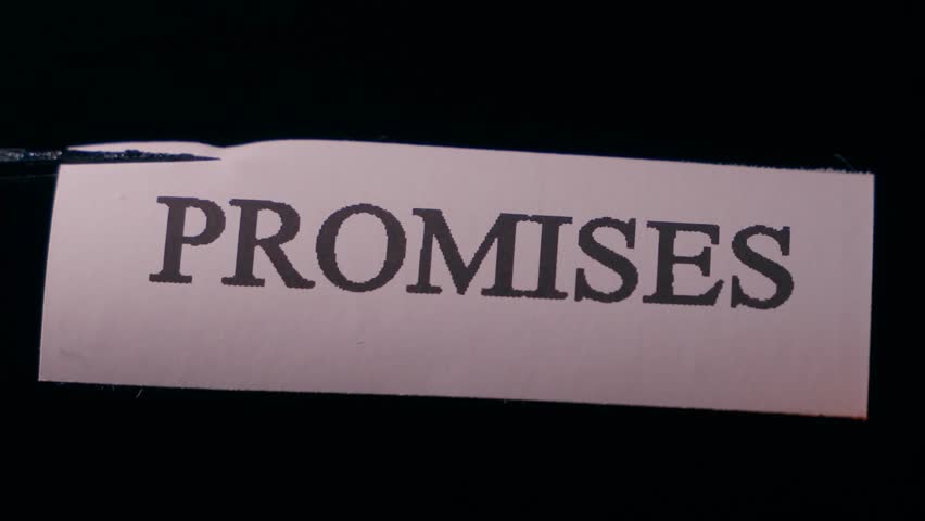 Burning promises, close-up on black background. Word PROMISES on paper being burned
