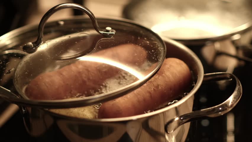 Sweet potatoes are boiling gently in a pot with a lid on, creating steam in an inviting kitchen setting during the evening.