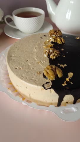 A cake with chocolate, nuts and cream on the table, next to a mug of tea, a kettle. Tea drinking at home and in a cafe