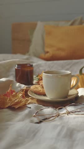 Cozy autumn morning scene with a warm coffee cup on bed, soft light and calm lifestyle mood.
