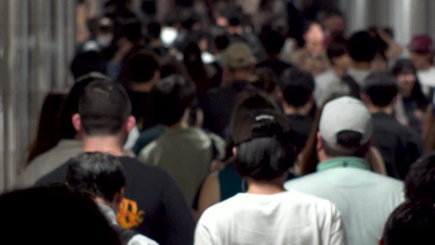 TOKYO, JAPAN - AUG 2025 : Crowd of people walking at the street near the station in busy night rush hour. Japanese people, urban city life and lifestyle concept video. Slow motion shot.
