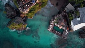 Overhead aerial video capturing dramatic ocean cliffs with seaside dining terraces and an infinity pool above clear blue water coral shallows and a calm coastal atmosphere during warm sunset light - Powered by Shutterstock - Get 15% off with code: PIKWIZARD15