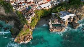 Aerial video of Suluban Beach Uluwatu showing limestone sea cliffs with oceanfront dining terraces, rock pool, clear blue ocean, reef flats and a calm tropical sunset atmosphere - Powered by Shutterstock - Get 15% off with code: PIKWIZARD15