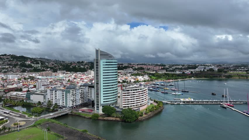 flying along central part of Fort-de-France, with Malecon,  Cruise Ship Terminal, Old town, Tour Lumina, and hilly landscape built-up in the background, situated in Martinique, Lesser Antilles, Caribbean - 4k aerial video footage