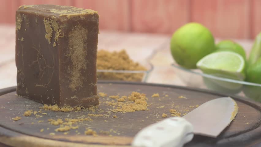 Woman grates panela with limes on sunny day, soft focus background