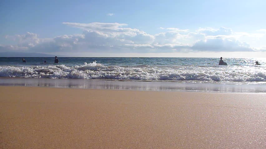 Waves crashing on sandy beach in sunny Hawaii.