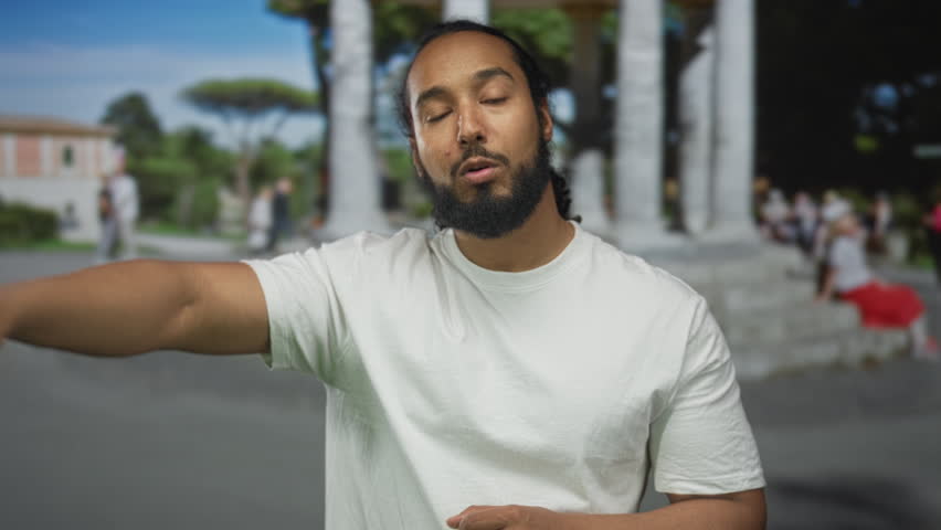 Man points finger at camera on street near stone monument with index finger extended; call to action surprise.