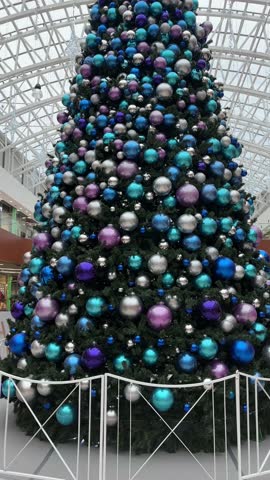 Christmas tree in shopping mall. Holiday decorations. Big elegant Christmas tree indoors at a shopping center. Vertical video