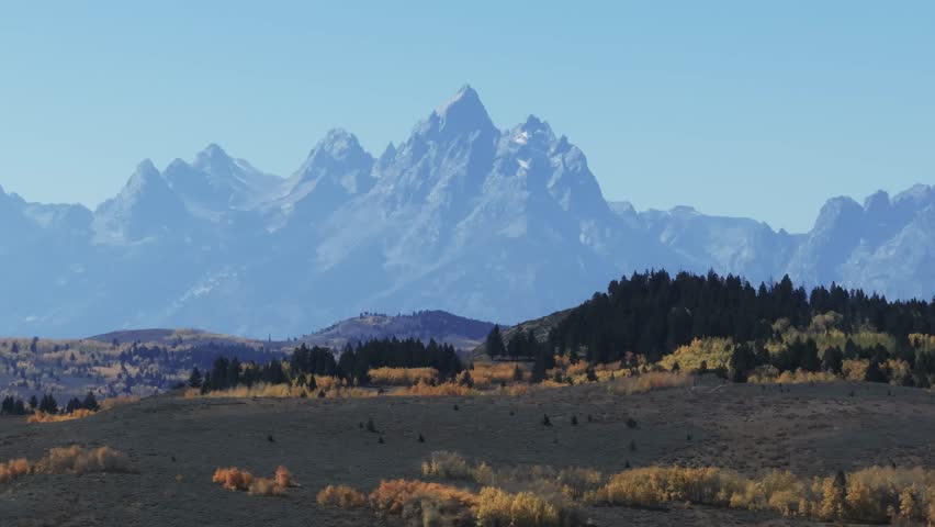Aerial footage of the Teton range during autumn with fall foliage.