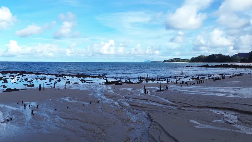 Aerial drone view of sandy Long Beach on Koh Lanta featuring turquoise water, gentle waves and a wide tropical coastline surrounded by lush greenery and calm island atmosphere.