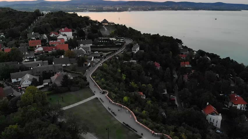Drone aerial over Tihany village road with people walking by Lake Balaton Hungary