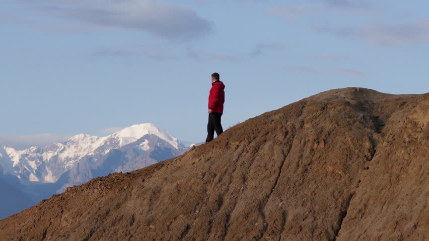 Man With A Camera Standing Over Mountain Overlooking Ak Sai Canyon In Kyrgyzstan. Aerial Drone Shot