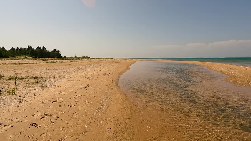 Wind ripples the surface of a small inlet of water on the beautiful beach of Lake Michigan. Located within Wilderness State Park in Northern Michigan, USA.