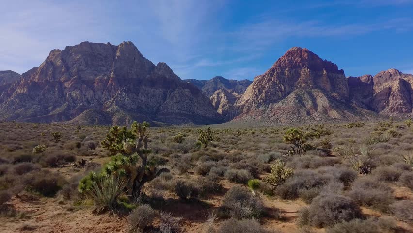 Aerial drone footage of a red rock canyon captured in the afternoon light, highlighting sandstone formations and desert terrain from above