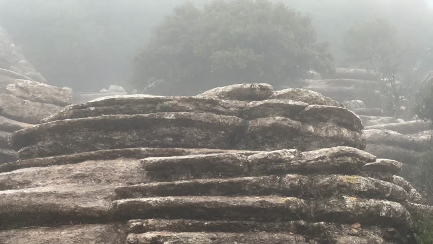 Unusual karst rock formations from the Jurassic era shrouded in dense morning mist. A captivating and melancholic scenery in a nature reserve in Spain