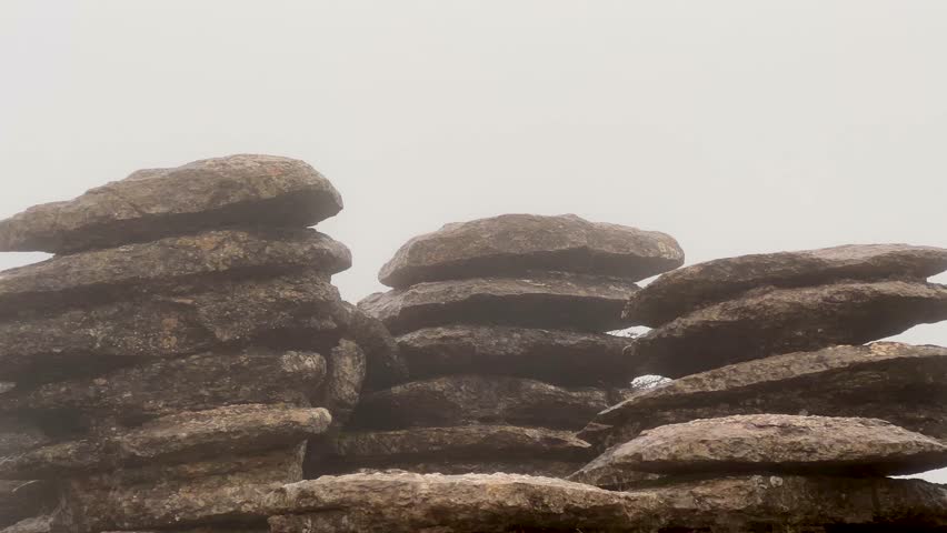 Enigmatic mist threading through El Torcal de Antequeras stacked limestone karst formations in Malaga, Spain, creating a mysterious, sculpted landscape for hiking and exploration